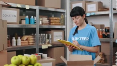 Bağış deposunu kontrol ederken panoya yazı yazan kadın