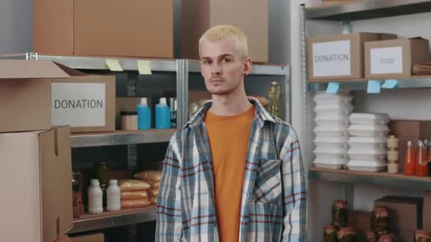 Hombre en ropa casual y pendientes posando en el almacén del banco de alimentos — Vídeos de Stock