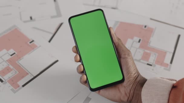 Man architect of ontwerper die smartphone met groene scherm mock-up chroma sleutel op de werkplek, bovenaanzicht. Lijntekening plattegrond op een achtergrond. Sluiten.. — Stockvideo
