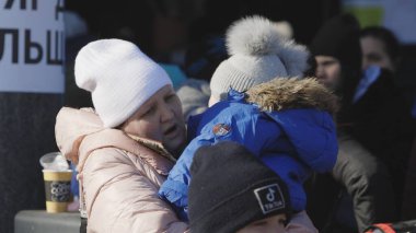 Lviv, Ukrayna - 15 Mart 2022: Ağlayan çocuğunu ellerinden tutan ve sakinleştiren kadın. Ukraynalı anne ve oğul mülteciler tren istasyonunda Avrupa 'ya kaçmak için bekliyorlar..