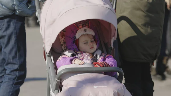 Lviv, Ukrayna - 15 Mart 2022: Çocuğunu bebek arabasında sakinleştiren ebeveyn. Ukraynalı mülteciler tren istasyonunda Avrupa 'ya kaçmak için bekliyorlar..