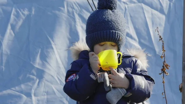 Lviv, Ukrayna - 15 Mart 2022: Lviv tren istasyonunda tren bekleyen mülteciler. Küçük çocuk evden ayrıldıktan sonra ayakta ve yemek yiyor..