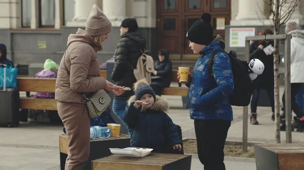 Lviv, Ukrayna - 15 Mart 2022: Batı Ukrayna 'nın Lviv kentindeki tren istasyonunda tahliye trenlerini bekleyen insanlar. Çocuklar annelerinin yanında yemek yer ya da gönüllü olurlar. Ukrayna 'da savaş kavramı.