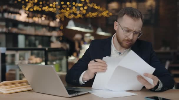 Affärsman kontrollera företagens pappersarbete korrespondens när du sitter på café. — Stockvideo