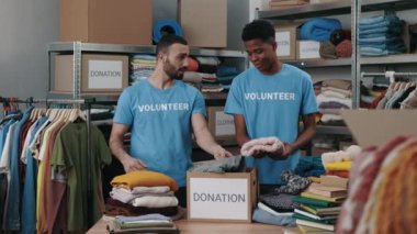 Bağış merkezinde çalışan ve dolaplara kıyafet koyan iki farklı erkek arkadaş. İnsani yardım ve gönüllüler konsepti.