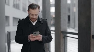İş adamı sokakta akıllı telefon ve mesaj kullanıyor.