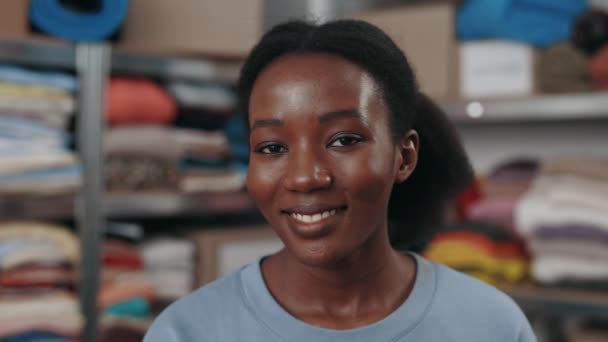 Çok ırklı mutlu kadının yeniden kullanım merkezinde çalışırken kameraya geniş bir gülümsemeyle bakışının portresi. İkinci el ve sürdürülebilirlik kavramı. — Stok video