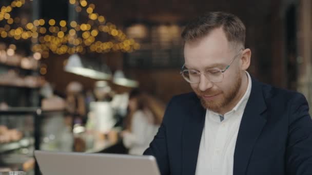 Úspěšný manažer pracující na notebooku v kavárně. Nadšený profesionál čte dobré zprávy. Šťastný chlapík si užívá vítězství. Obchodník ukazuje ano gesto. — Stock video
