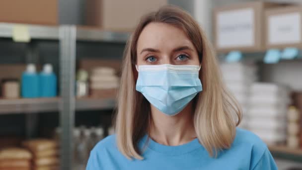 Portrait of female volunteer face mask posing at food bank — Stock Video