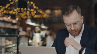 İş adamı kafede çalışırken öksürüyor. Hasta çalışan kendini kötü hissediyor..