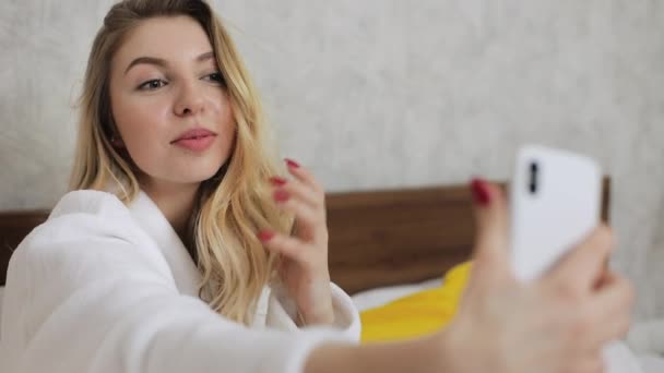 Frau macht Selfie an ihrem Gerät, während sie im Bett sitzt Technologisches Konzept. — Stockvideo