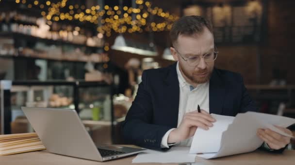Affärsman som gör pappersarbete. Man tittar igenom arbetspapper medan man sitter. — Stockvideo