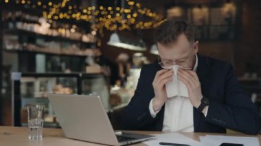 Kafede çalışan hasta bir işadamı ve burnu akıyor. Hasta erkek burun sümkürme.