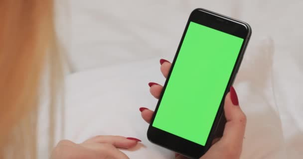 Womans holding mobile telephone with green screen and looking at the display. — ストック動画