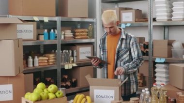 Bağış kutuları paketlenirken dijital tablet kullanan adam