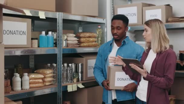 Homem e mulher usando comprimido para inspecionar o armazenamento do banco de alimentos — Vídeo de Stock