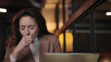 Modern dizüstü bilgisayarlı hasta iş kadını rahat kafede öksürüyor.