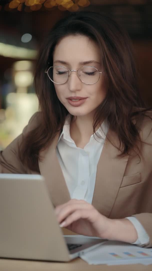 Urocza kobieta uśmiechnięta do kamery podczas pracy na laptopie — Wideo stockowe