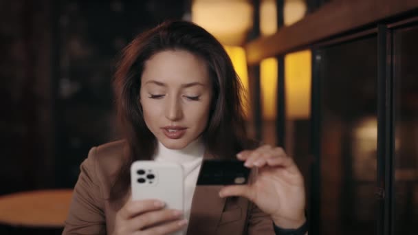 女人坐在咖啡店里用带有信用卡的智能手机 — 图库视频影像