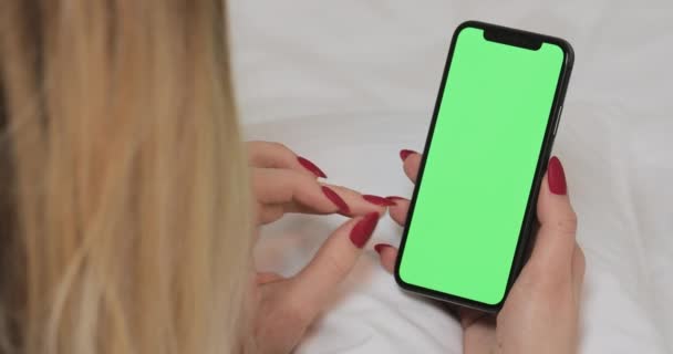 LVIV, UKRAINE- 5 March 2022: Businesswoman slides green chroma key screen on her smartphone device with finger. Woman holding phone in hands, swipes left . Green mock up chromakey screen. Close up, — ストック動画