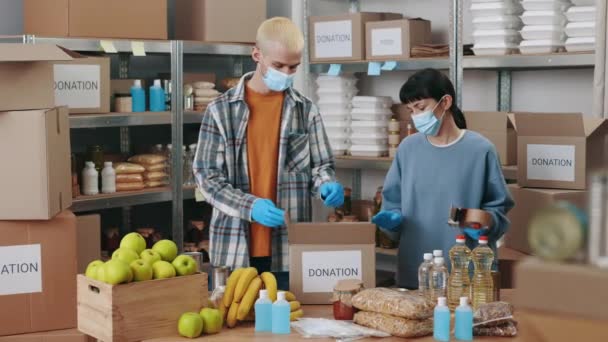 Group of volunteers in face masks packing donation boxes — 비디오