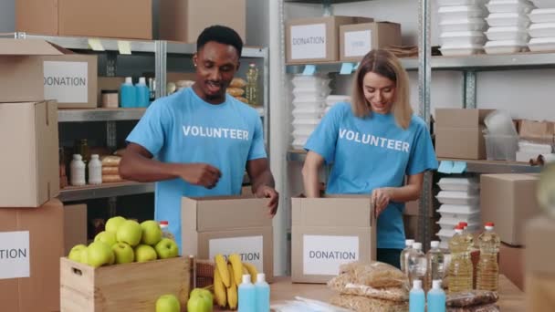 倉庫での寄付のために食べ物を分類する多様なボランティア — ストック動画
