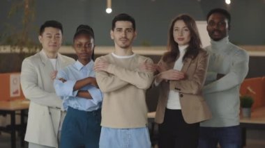 Başarılı iş adamlarının portresi ofis odasında durup kollarını kavuşturmuş kameraya bakıyor. Çok ırklı profesyonel çalışanlar takım portresi ve liderlik için birlikte poz veriyorlar..