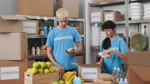 Male and female volunteers packing food donations — Stock Video