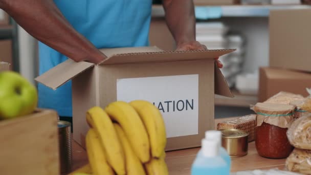 Zbliżenie samców ochotników wypełniających kartonowe pudełka darowizn — Wideo stockowe