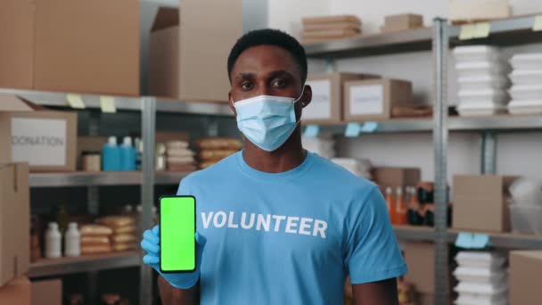 Man met masker met groen scherm mobiel bij de voedselbank — Stockvideo