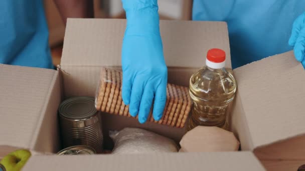 Dobrovolníci v rukavicích plnící kartónové krabice pro charitu — Stock video