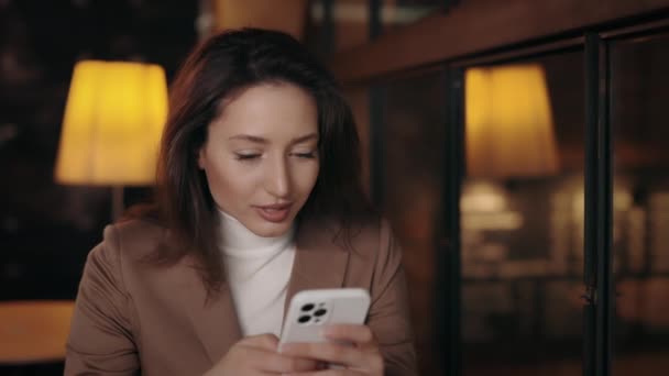 Жінка отримує шокуючі хороші новини на смартфоні в кафе — стокове відео