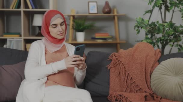 Evde cep telefonu kullanan tesettürlü hamile bir Arap kadın. — Stok video