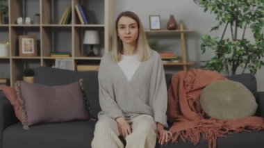 Gülümseyen beyaz kadın, evinde, yumuşak koltukta dinleniyor.