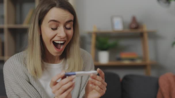 Heyecanlı kadın evde pozitif hamilelik testine bakıyor. — Stok video