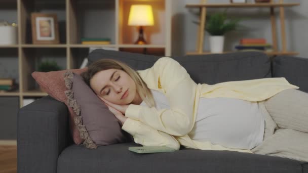 Tired pregnant woman napping on sofa at home — Wideo stockowe