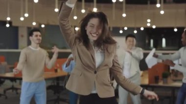 İş arkadaşlarıyla dans eden Kafkasyalı komik iş kadını şirket başarısını kutluyor ofis partisinde iyi eğlenceler. Mutlu iş arkadaşları grubu eğleniyor Başarı, zafer, ofis hayatı.