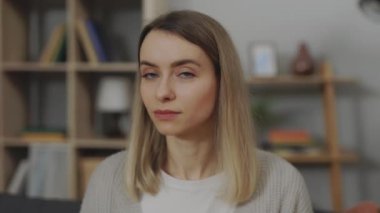 Oturma odasında oturan gülümseyen beyaz kadın portresi.