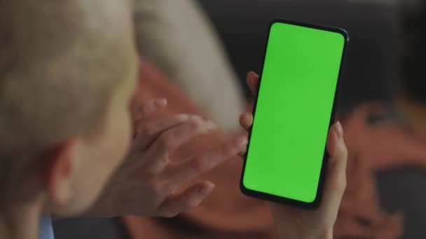 Woman tapping finger on green screen of smartphone at home — ストック動画