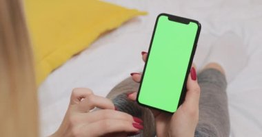 LVIV, UKRAINE- 5 March 2022: Woman using modern smartphone with chroma key mock-up screen.