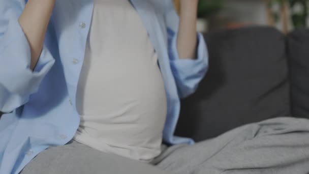 Future maman mettre des écouteurs sur le ventre tout en étant assis sur le canapé — Video