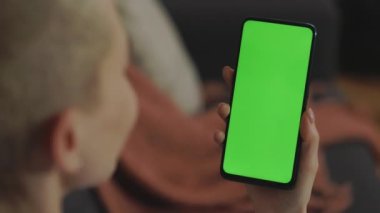 Elinde yeşil ekranlı akıllı telefon tutan kadın.