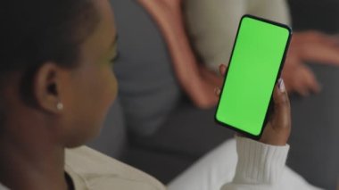 Elinde yeşil ekranlı akıllı telefon tutan kadının arka planı