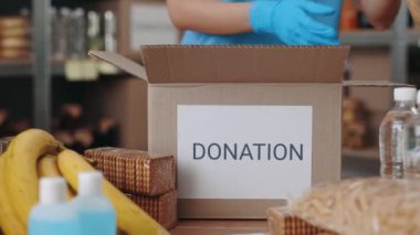 Close up of volunteer in gloves packing donation boxes