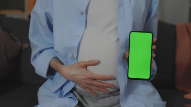 Mujer acariciando la barriga y sosteniendo el teléfono con pantalla verde — Vídeo de stock