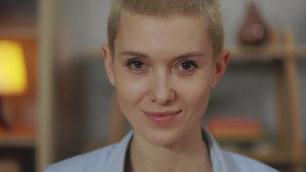 Mujer sonriente con corte de pelo corto mirando a la cámara en casa — Vídeos de Stock