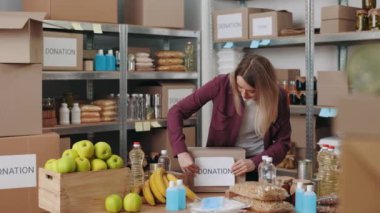 Kadın gönüllü gıda bankasında bağış kutuları hazırlıyor.
