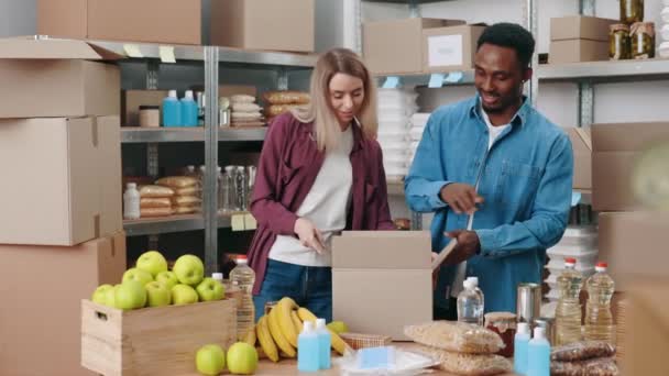 Férfiak és nők dobozokat pakolnak élelmiszerrel a raktárban — Stock videók