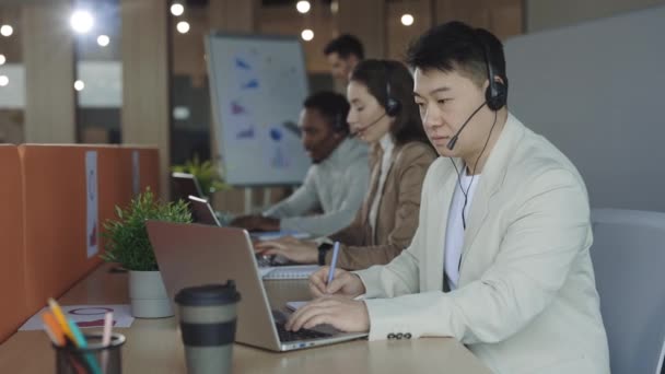 Mannelijke operator met laptop in gesprek met klant in headset — Stockvideo
