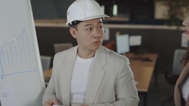 Asian architect explaining idea to colleagues near flipchart — Stock Video